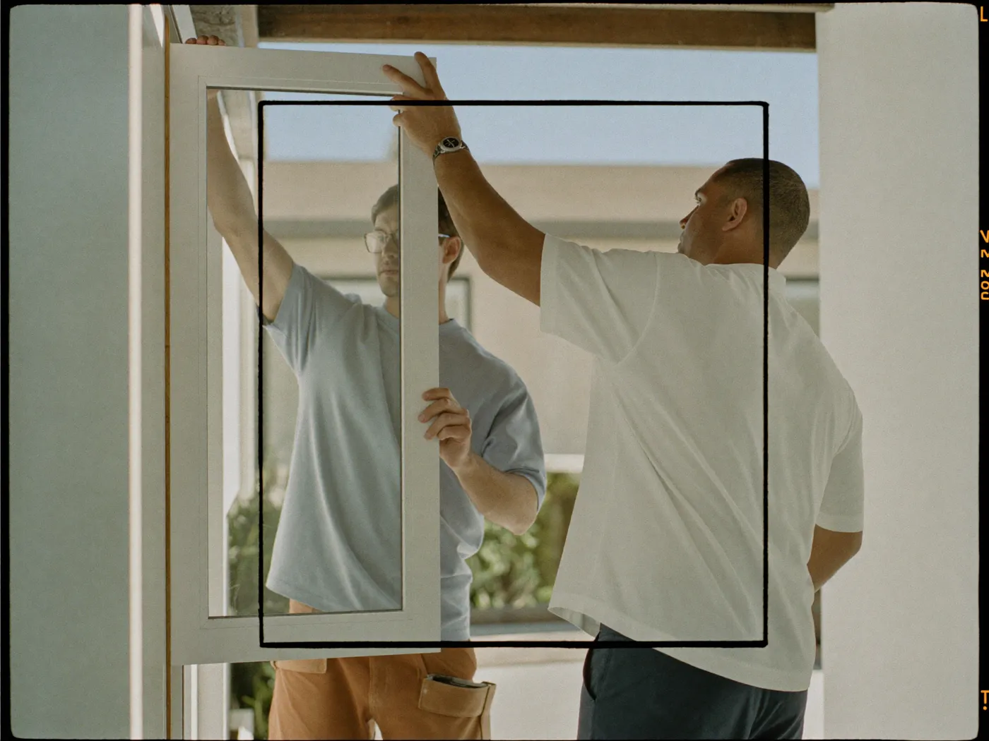 An installation crew fitting a large new window in a bright home